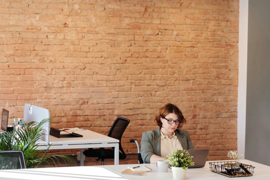 employee at a desk in an office with a brick wall in the background